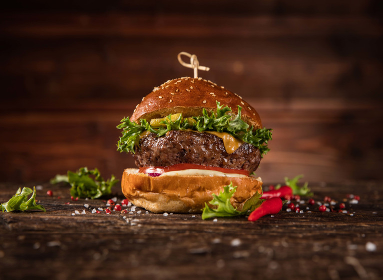 Plato de hamburguesa de cerdo madurada con salsa de queso y pepinillos